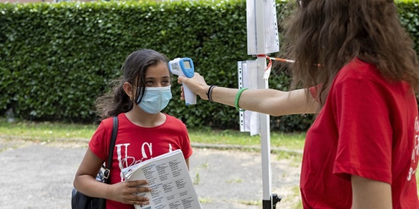 una operatrice misura la febbre con il termo scanner a una bambina con la mascherina chirurgica