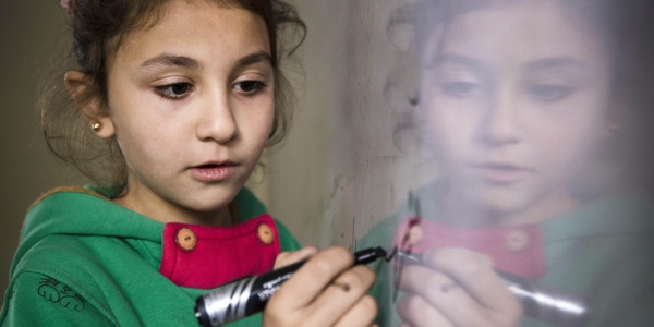 bambina scrive su una lavagna magnetica con un pennarello nero