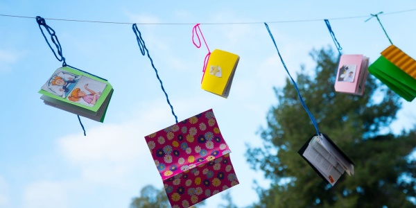 Libri e quaderni colorati appesi a un filo che si stagliano su cielo azzurro