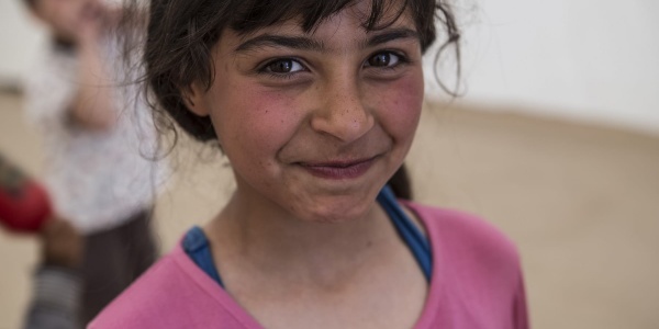 Primo pano di bambina bionda con capelli biondi legati e sguardo sorridente