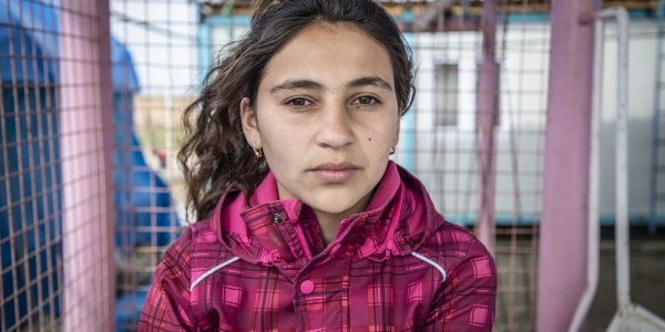 Mezzo busto di una bambina siriana castana in campo per sfollati con giacca rosa