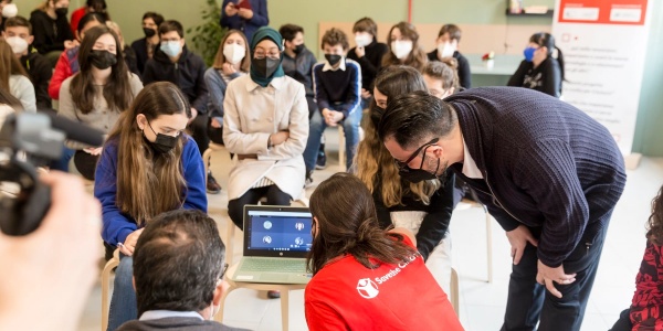 in una classe di studenti quattro persone sono sedute attorno ad un pc e lo guardano. Una è operatrice save the children