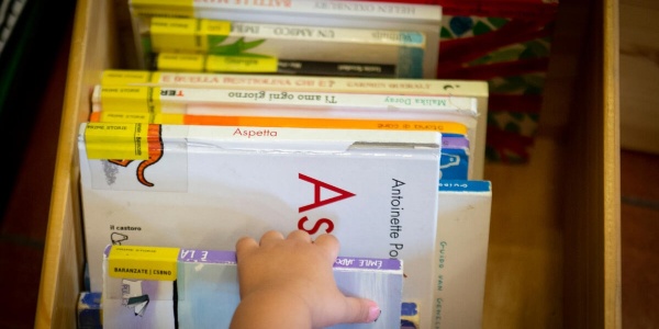 mano di un bambino che sceglie da una scatola di libri