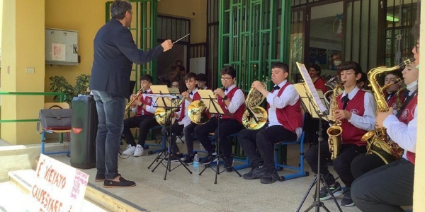 Insegnante che dirige l'orchestra di studenti che suonano strumenti musicali come trombe e flauti