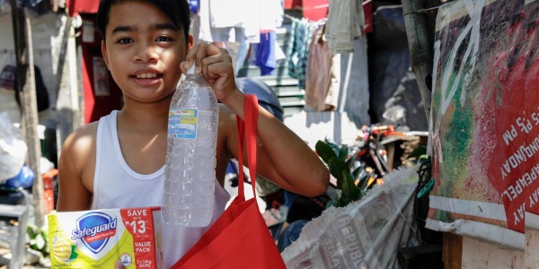 bambino asiatico tiene una bottiglia di acqua e un kit igienico sanitario in mano