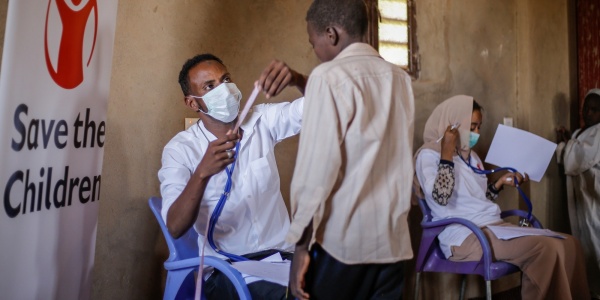 Sudan un operatore con mascherina visita un bambino in piedi di fronte a lui