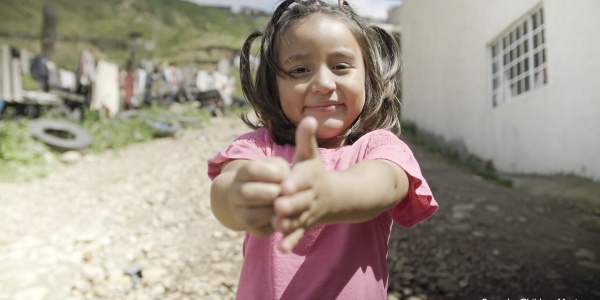 Una bambina messicana con codini e maglietta rosa mostra come ha imparato a lavarsi le mani.