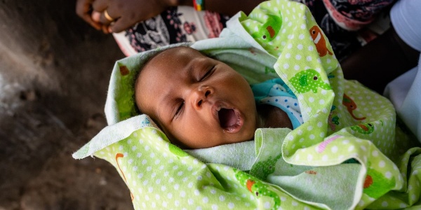 Primo piano neonato africano che sbadiglia avvolto in copertina verde