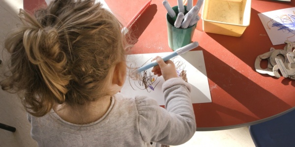 bambina di spalle alla scrivania che colora e disegna