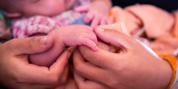 dettaglio delle mani di una mamma che tengono la mano del suo neonato