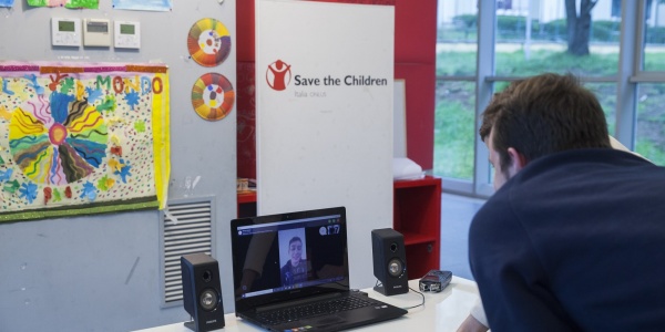 operatore di save the children italia davanti al pc in collegamento con un ragazzo