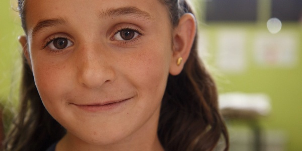 Primo piano di una bambina bionda sorridente che guarda in camera