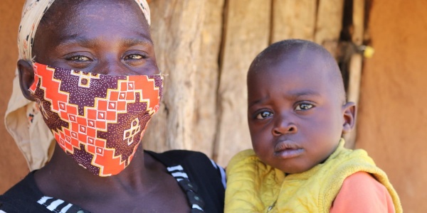 Mamma dello Zimbabwe con mascherina anti-covid tiene in braccio il suo bambino