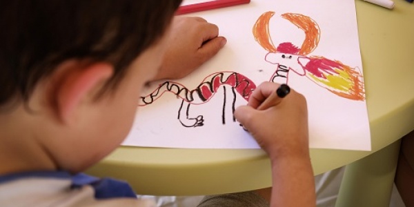 bambino di spalle che disegna un drago