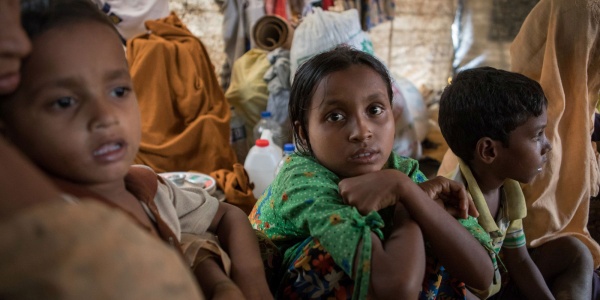 Una bambina e due bambini rohingya seduti vicini