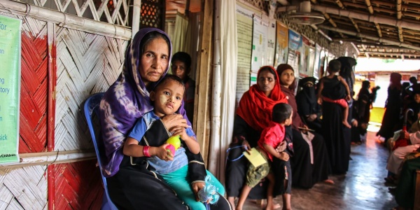 Donna Rohingya tiene in braccio suo figlio seduta in un tendone del campo profughi cox s bazar