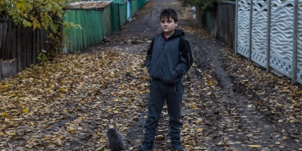 bambino ucraino posa in piedi su una strada ricoperta di foglie 