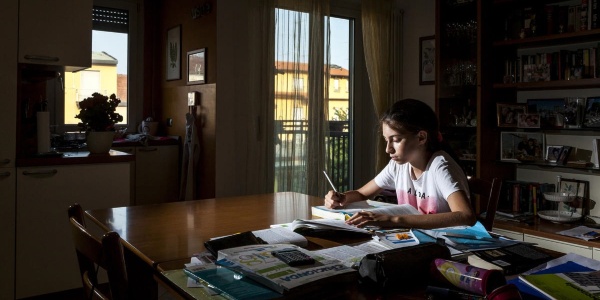 Immagine di una bambina impegnata a studiare in una stanza buia