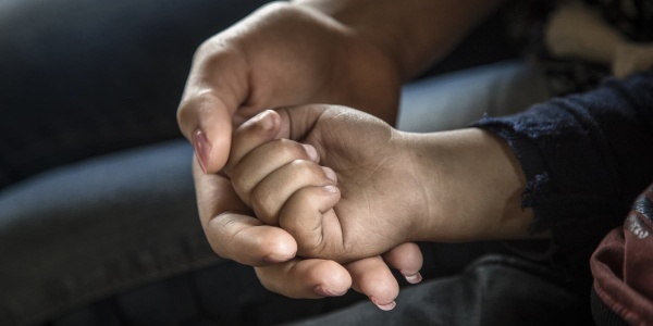 Primo piano di mano di donna che tiene nella sua la mano di un bambino piccolo