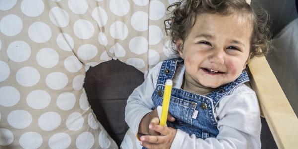 bambina bianca con i capelli ricci seduta con in mano un pennarello giallo