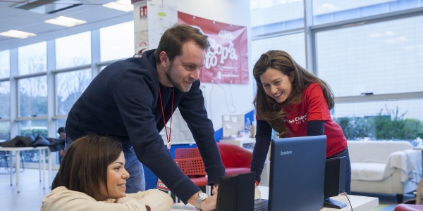 Tre operatori Save the Children guardano un pc appoggiato su un tavolo