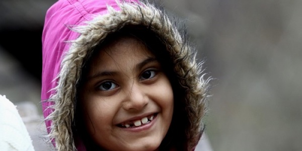 Emergenza freddo bambina con cappotto rosa e cappuccio che ride