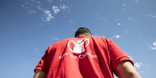 Operatore save the children di spalle con il cielo di sfondo