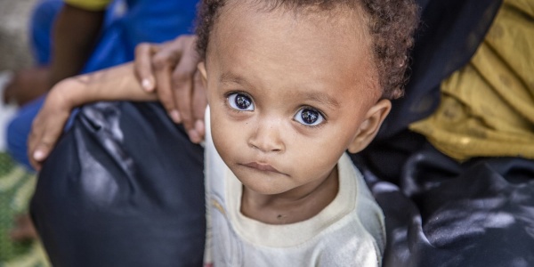 Primo piano di un bambino yemenita tra le gambe di un adulto