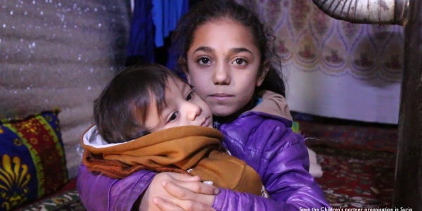 Freddo Siria bambina con cappotto viola tiene in braccio un bambino