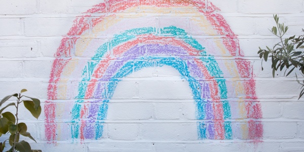 arcobaleno fatto con gessetti colorati su muro bianco