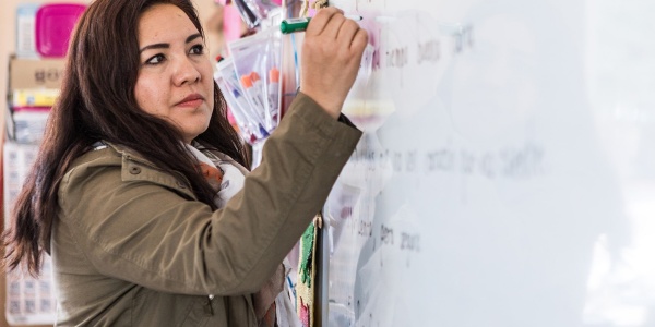 insegnante scrive alla lavagna con un pennarello in aula