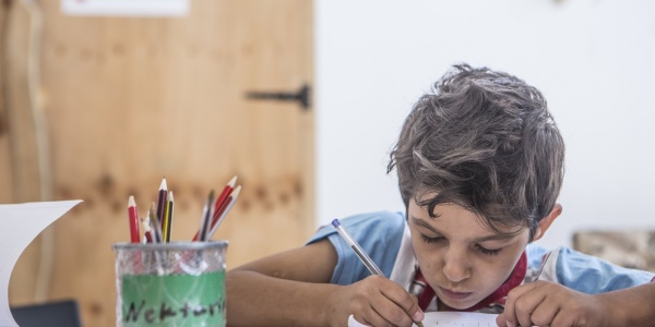 Bambino siriano fa i compiti al banco di scuola