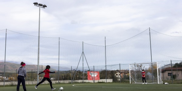 campetto di calcio con due bambini che giocano in lontananza, uno con maglietta rossa e pantaloni neri l altro con maglietta grigia e pantalone nero