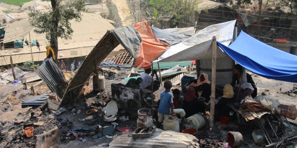Tenda di fortuna nel mezzo di cenere e resti incendiati nel campo di coxs bazar in bangladesh. Sotto la tenda si ripara una famiglia Rohingya di varie persone