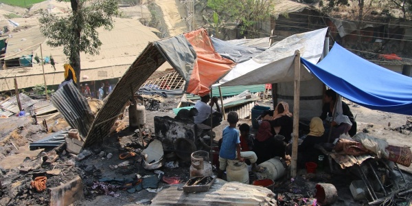 Tenda di fortuna nel mezzo di cenere e resti incendiati nel campo di coxs bazar in bangladesh. Sotto la tenda si ripara una famiglia Rohingya di varie persone 