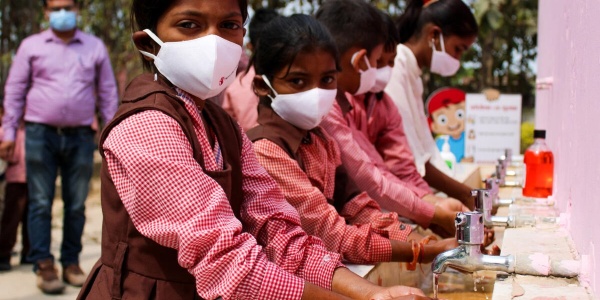 Bambine indiane che si lavano le mani e indossano una mascherina