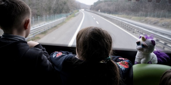 Due bambini di spalle a bordo di un autobus guardano la strada davanti a loro