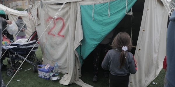 bambina di spalle di fronte a una tenda in accampamento di risposta al terremoto in Albania