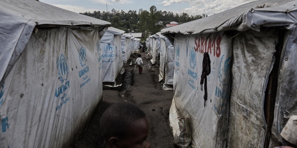 bambina voltata di lato tra le tende di un campo per sfollati 