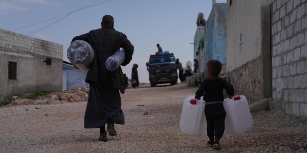 padre e bambino in Siria che trasportano taniche e sacchi dopo il terremoto che ha colpito Turchia e Siria