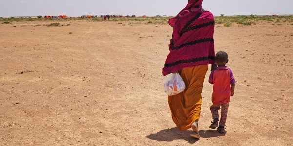 donna somala che cammina tenendo per mano un bambino 