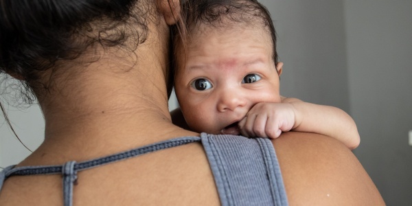 mamma di spalle con in braccio il suo neonato che guarda in camera