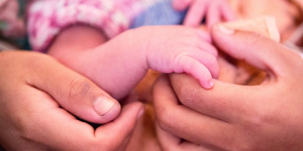 Mani di una mamma tengono la mano di suo figlio neonato