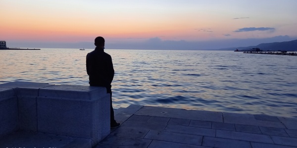 uomo di spalle guarda l'orizzonte sul mare