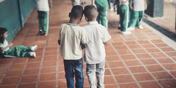 due bambini di spalle vicini che camminano verso un gruppo di bambini e bambine