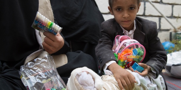 Bambino yemenita con gamba ingessata seduto con giochi in mano