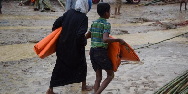 bambino con madre che scappano su un terreno fangoso in Myanmar
