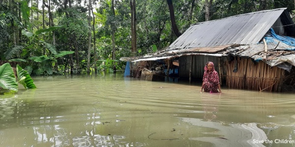 Una donna vicino alla sua capanna è immersa fino alla pancia nell acqua di un inondazione