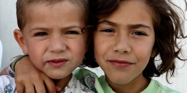 due bambini in primo piano, uno con i capelli corti l altro lunghi, uno con il braccio sulla spalla dell altro