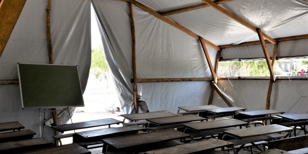 Aula con banchi di scuola e lavagna allestita in un tendone